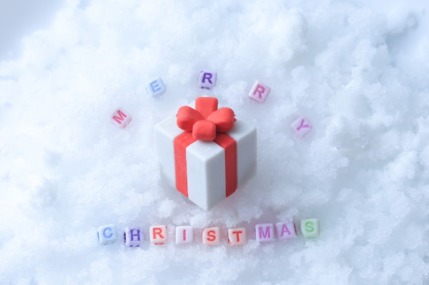 Messaggio di buon Natale fatto con cubetti di lettera sulla neve e confezione regalo