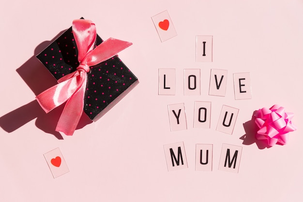 Messaggio di Happy Mothers Day con i cuori rossi su fondo rosa luminoso concetto della cartolina d'auguri. Messaggio di Mothers Day. Regalo e testo