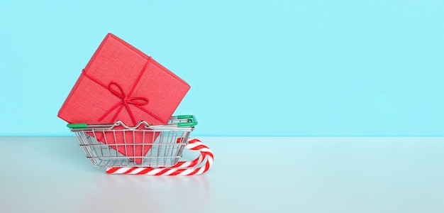 Messaggio di vendita di Natale con carrello del negozio e regalo bianco. Super giorno di vendita o concetto di giorno dei single. Carrello della spesa, confezione regalo su sfondo di carta blu. Vendita di Natale. Banner per le vendite.