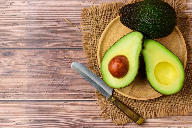 Metà dell'avocado sul piatto di legno. Avocado verde fresco maturo