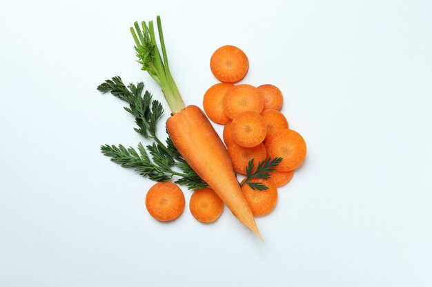 Metà della carota, delle fette e delle foglie su fondo bianco