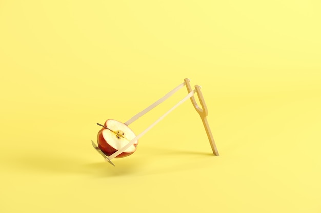 Metà della mela rossa in una fionda su sfondo giallo