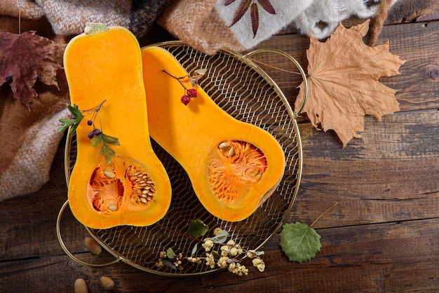 Metà della zucca sul vassoio in metallo dorato sulla vista dall'alto del concetto di raccolta autunnale della tavola di legno