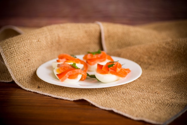 metà delle uova sode con pezzi di salmone salato su un tavolo di legno