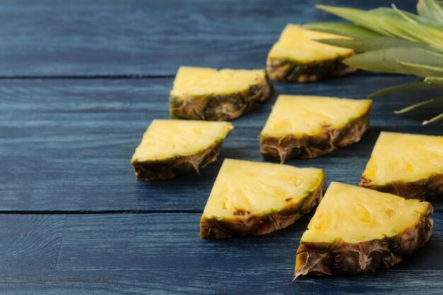 Metà di ananas maturo fresco e fette di ananas su fondo di legno blu frutti estivi