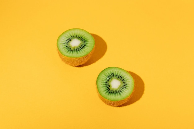 Metà di kiwi succosi maturi su sfondo giallo