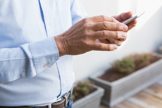 Metà di sezione dell&#39;uomo che utilizza smartphone a casa nel giardino