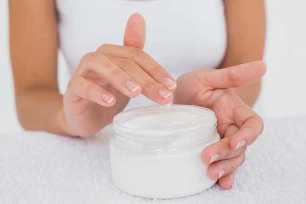 Metà di sezione della donna che applica crema