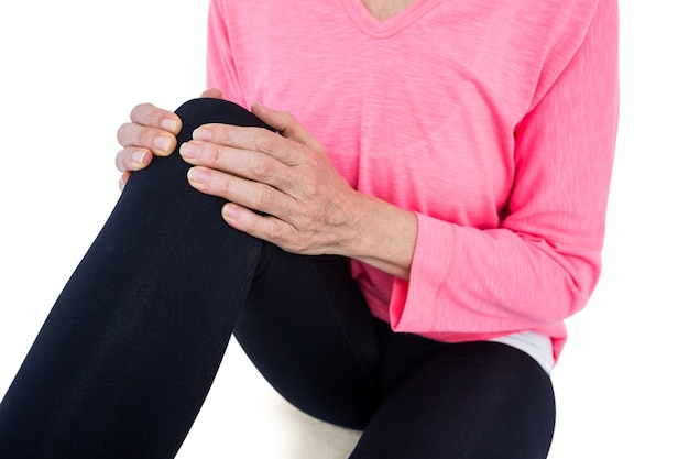 Metà di sezione della donna matura che massaggia ginocchio