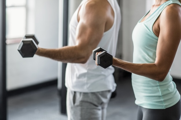 Metà di sezione delle coppie che si esercitano con i dumbbells in ginnastica