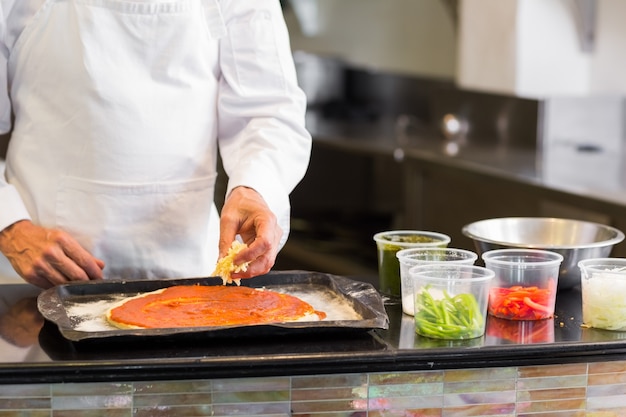 Metà di sezione di un cuoco unico maschio che prepara pizza