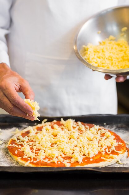 Metà di sezione di un cuoco unico maschio che prepara pizza