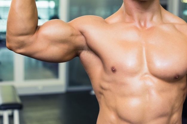 Metà di sezione di un uomo muscolare senza camicia in palestra