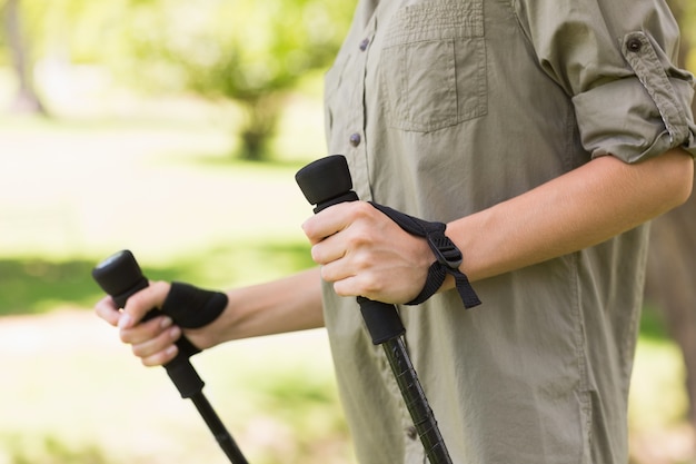 Metà di sezione di una donna che cammina nordico nel parco