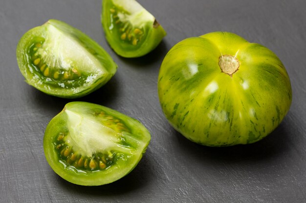 Metà di un pomodoro verde un pomodoro intero su sfondo grigio