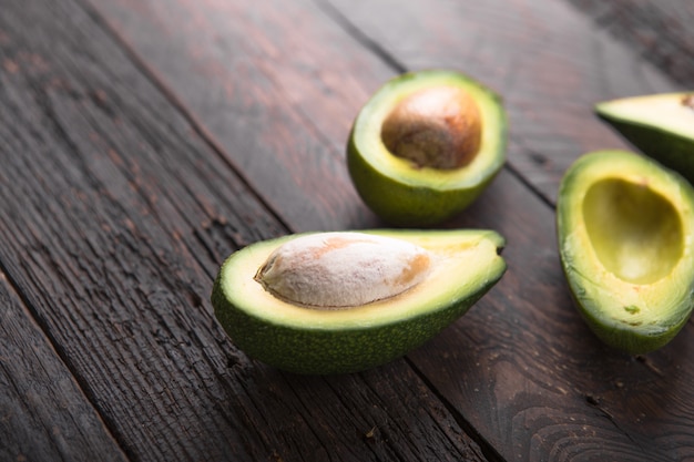 Metà organiche fresche dell'avocado sulla vecchia superficie di legno della tavola Concetto sano dell'alimento con lo spazio della copia.