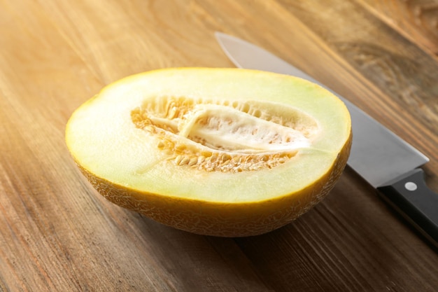 Metà squisita del melone e del coltello sulla tavola di legno