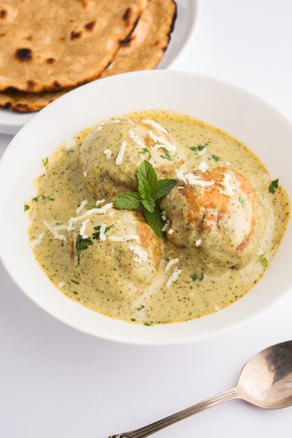 Methi Malai Kofta in stile Mughlai o Haryanvi in crema bianca, piatto principale vegetariano indiano popolare servito in una ciotola di legno con Chapati o Roti, messa a fuoco selettiva