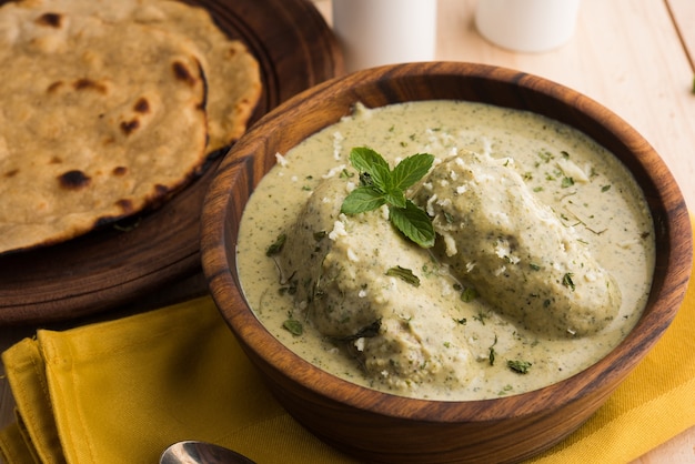 Methi Malai Kofta in stile Mughlai o Haryanvi in crema bianca, piatto principale vegetariano indiano popolare servito in una ciotola di legno con Chapati o Roti, messa a fuoco selettiva