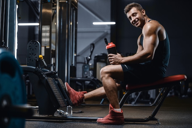 Metta in mostra l'acqua potabile dell'uomo muscolare di forma fisica dopo l'allenamento