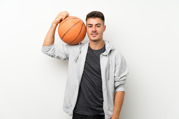 Metta in mostra l'uomo sopra la parete bianca isolata con la palla di pallacanestro