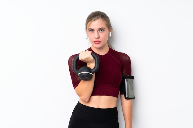 Metta in mostra la ragazza dell'adolescente sopra sollevamento pesi di fabbricazione bianco con kettlebell e guardare alla parte anteriore