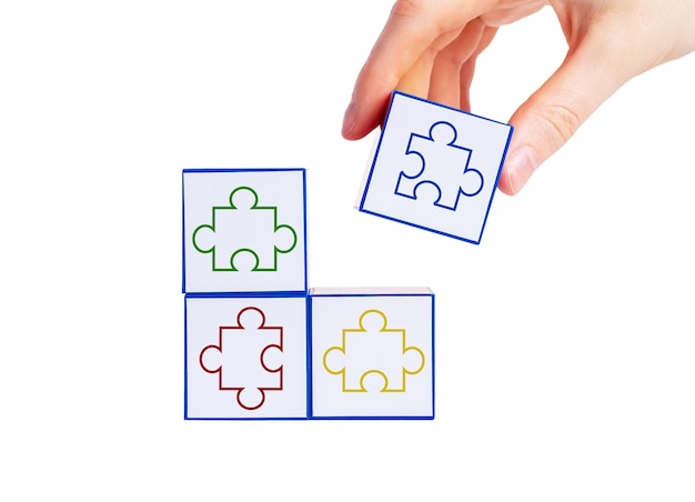 Mettendo a mano i cubi con i pezzi di puzzle colorati insieme isolati su sfondo bianco Trovare una soluzione dal concetto di strategia del problema logico di una situazione difficile