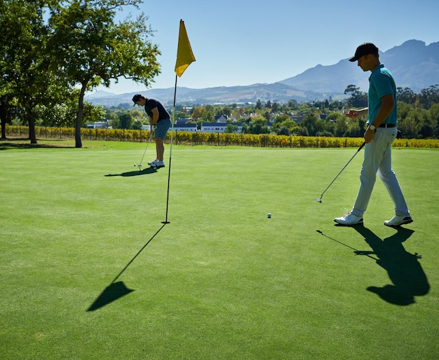 Mettere l'intera giornata Inquadratura di due giovani concentrati che giocano a golf fuori su un campo da golf