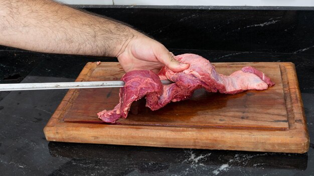 mettere la bistecca di fianco su uno spiedino metallico, sopra un tagliere di legno