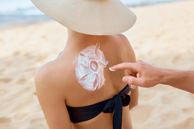 Mettere la lozione solare sulla pelle femminile e la cura del corpo Uomo che applica una crema solare protettiva