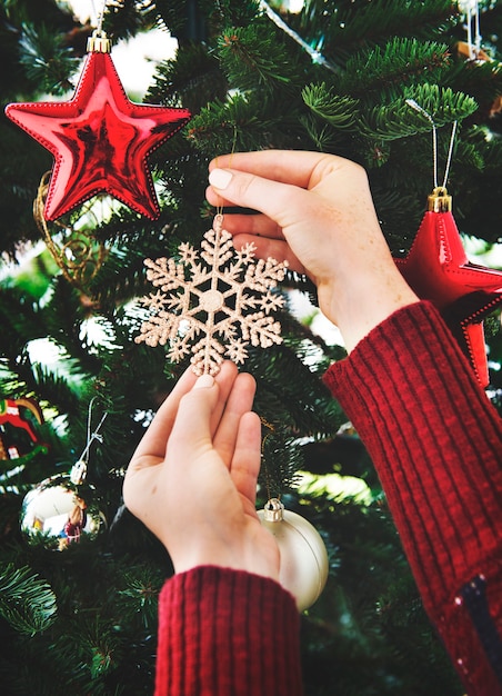 Mettere una decorazione a fiocco di neve sull'albero di Natale