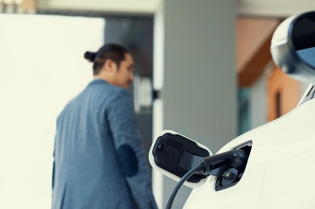 Metti a fuoco la stazione di ricarica EV a casa con l'uomo progressivo sfocato sullo sfondo