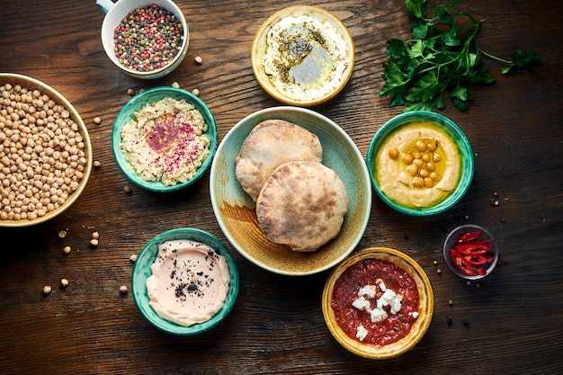 Meze è un set di antipasti orientali serviti in piccole ciotole con pita su un tavolo di legno. Hummus, yogurt, mousse di feta in ciotole con pane. Vista dall'alto