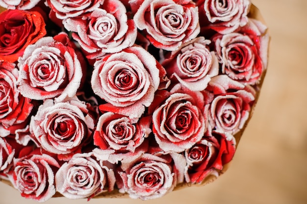 Mezza immagine del romantico bouquet rotondo di rose rosse a forma di pione decorate con polvere bianca