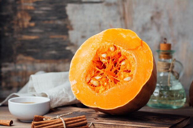 Mezza zucca cruda matura con semi su un tagliere su un tavolo di legno. Cibo vegetariano. Stile rustico