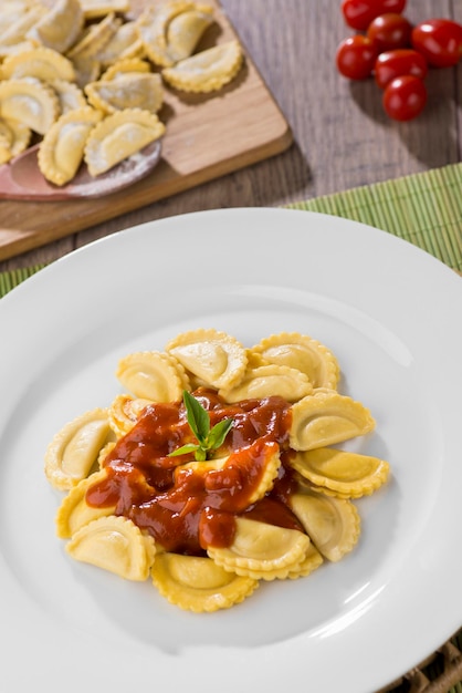 Mezzelune servita su piatto bianco, con pomodorini in sottofondo.