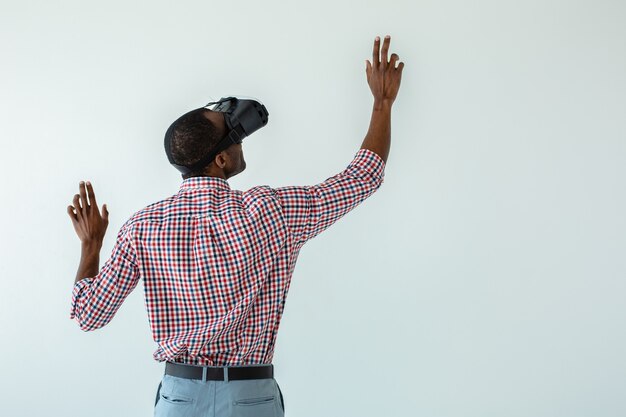 Mezzo busto di un piacevole uomo afroamericano utilizzando la lavagna virtuale mentre si trovava contro il muro bianco