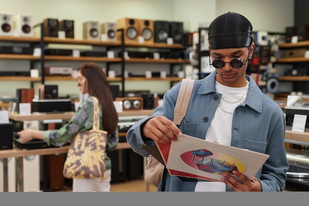 Mezzo busto ritratto di giovane uomo nero che tiene set di dischi in vinile nello spazio della copia del negozio di musica
