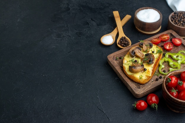 Mezzo colpo di gustoso spuntino con funghi e verdure tritate su tavola di legno posate con spezie su sfondo nero