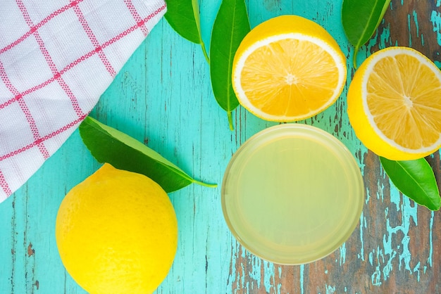 Mezzo limone e succo di limone spremere in una tazzina posta su un vecchio tavolo di legno verde