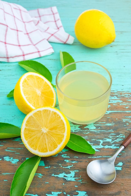 Mezzo limone e succo di limone spremere in una tazzina posta su un vecchio tavolo di legno verde