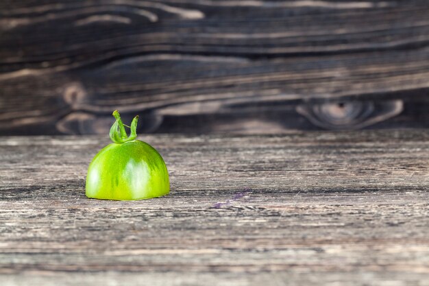 Mezzo pomodoro verde su un bordo verniciato nero, primo piano