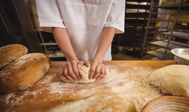 Mezzo sezione del panettiere femminile che impasta una pasta