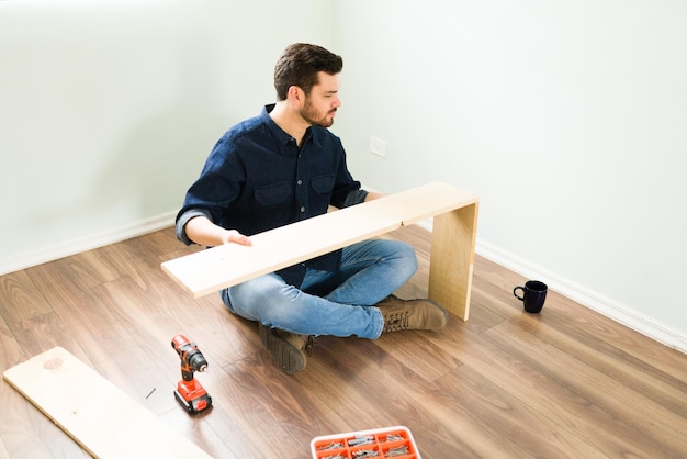 Mi piace fare i miei mobili. Giovane ispanico e tuttofare che costruisce un nuovo scaffale di legno per la sua casa