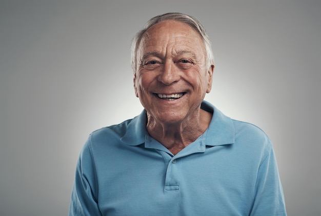 Mi sento come se fossi sulla nuvola 9 oggi Foto di un uomo che sorride felicemente alla telecamera in uno studio su uno sfondo grigio