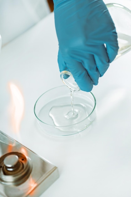 Microbiologia Mani di un microbiologo che versano agar in una capsula di Petri