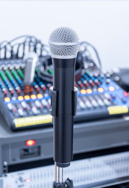 Microfono su treppiede al centro dell'immagine con sfondo di controllo del suono del mixer