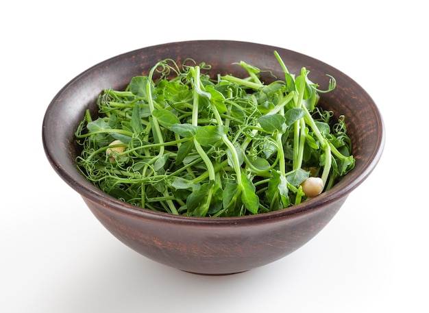 Microgreens freschi di pisello in ciotola di ceramica isolata su sfondo bianco con percorso di ritaglio