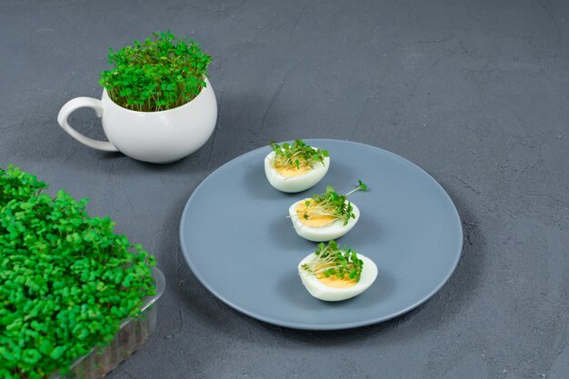 Microgreens su uova Decorare l'insalata con foglie di microgreens Alimento dietetico Uova sode e fresche su uno sfondo di microgreens freschi e croccanti