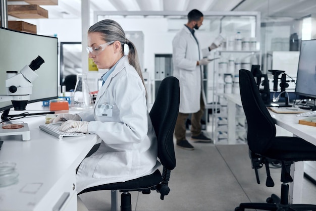 Microscopio donna da laboratorio o computer che digita nella ricerca sul cancro innovazione sanitaria medica o medicina assicurativa Scienziato del DNA maturo o idee scientifiche con l'uomo nello studio di collaborazione del lavoro di squadra